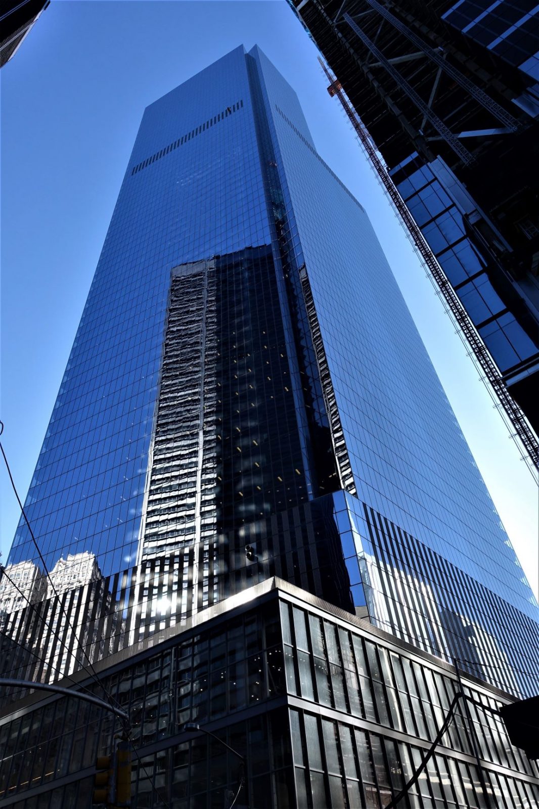 en skyskraper med glassfasade hvor nabobygningene speiler seg